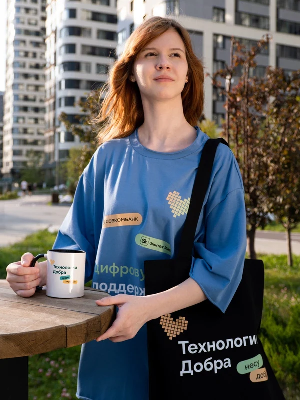 Синяя футболка с рисунком на человеке, рядом брендированная сумка